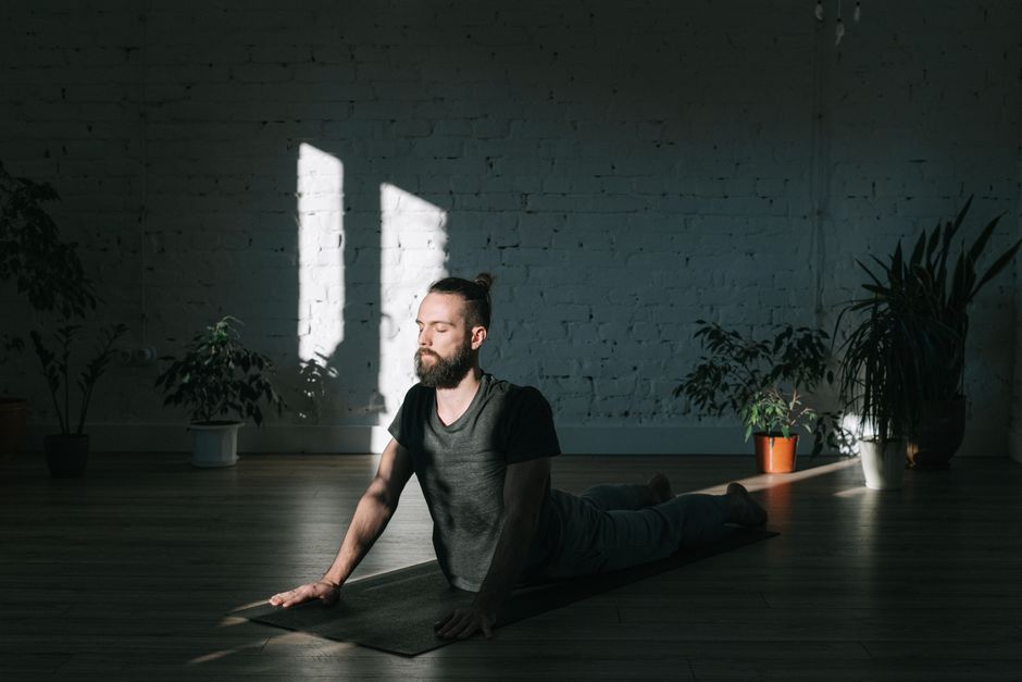 A serene yoga studio bathed in soft morning light, with rolled yoga mats, green plants, and open space